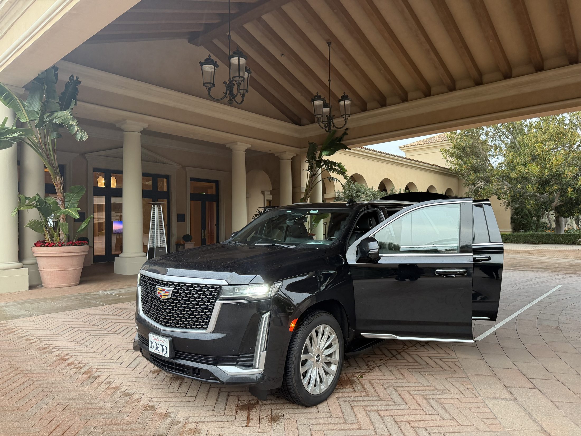 Luxier Cadillac Escalade at a resort porte-cochère, rear door open