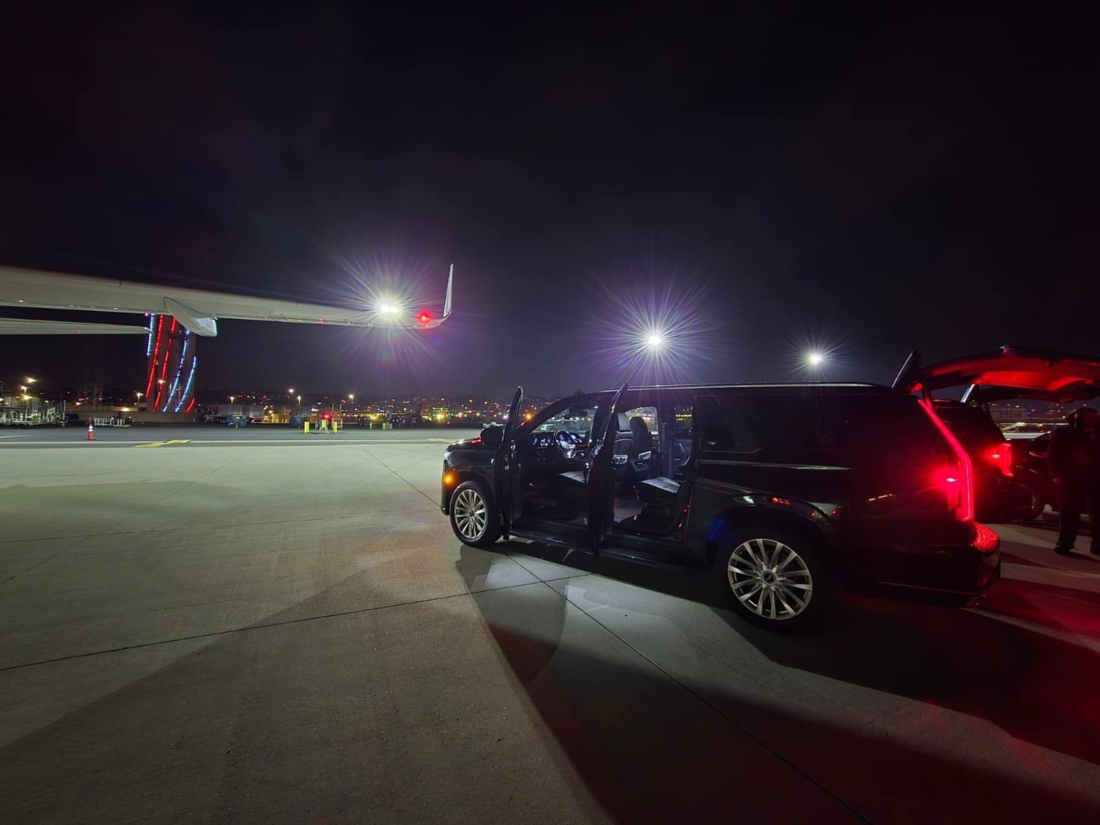 Luxier Escalade waiting planeside at night beside a private jet